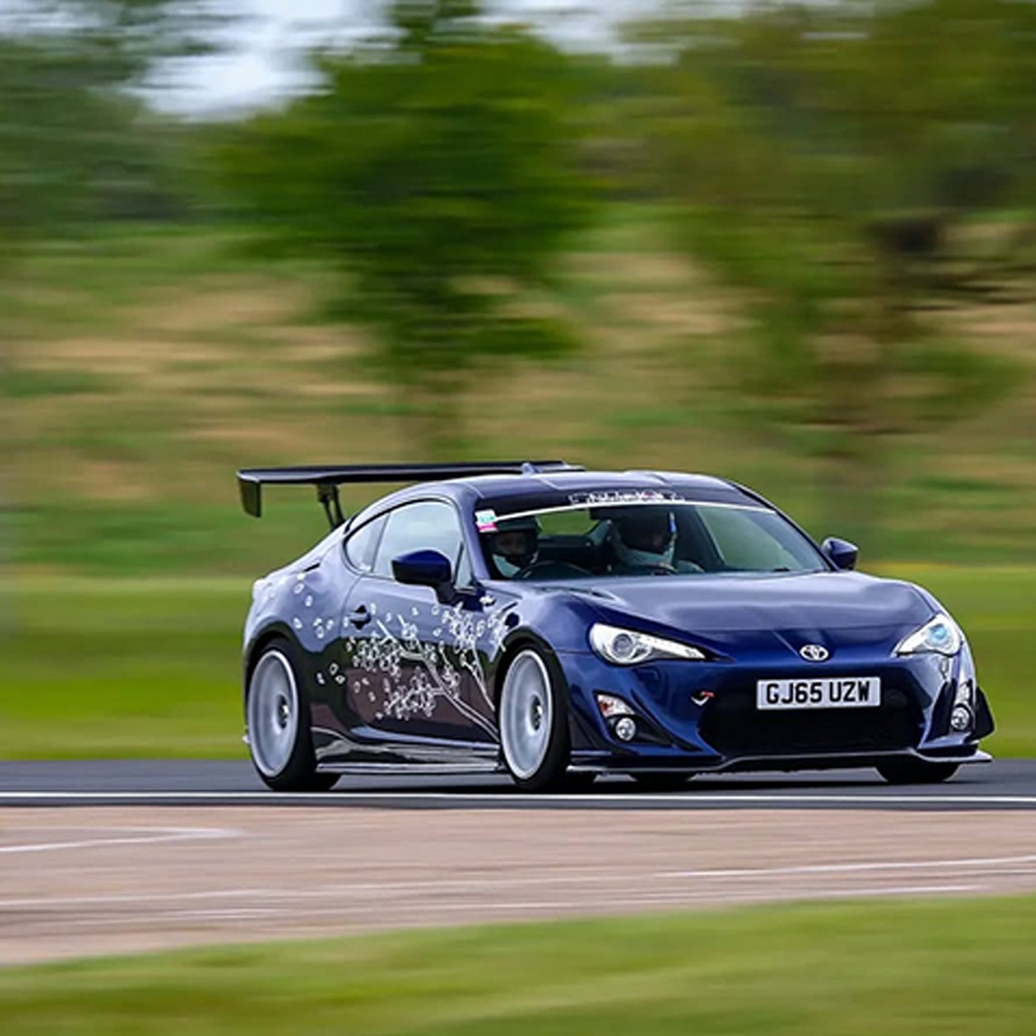 Blue Toyota car on a track with blurred background and blossom sakura livery