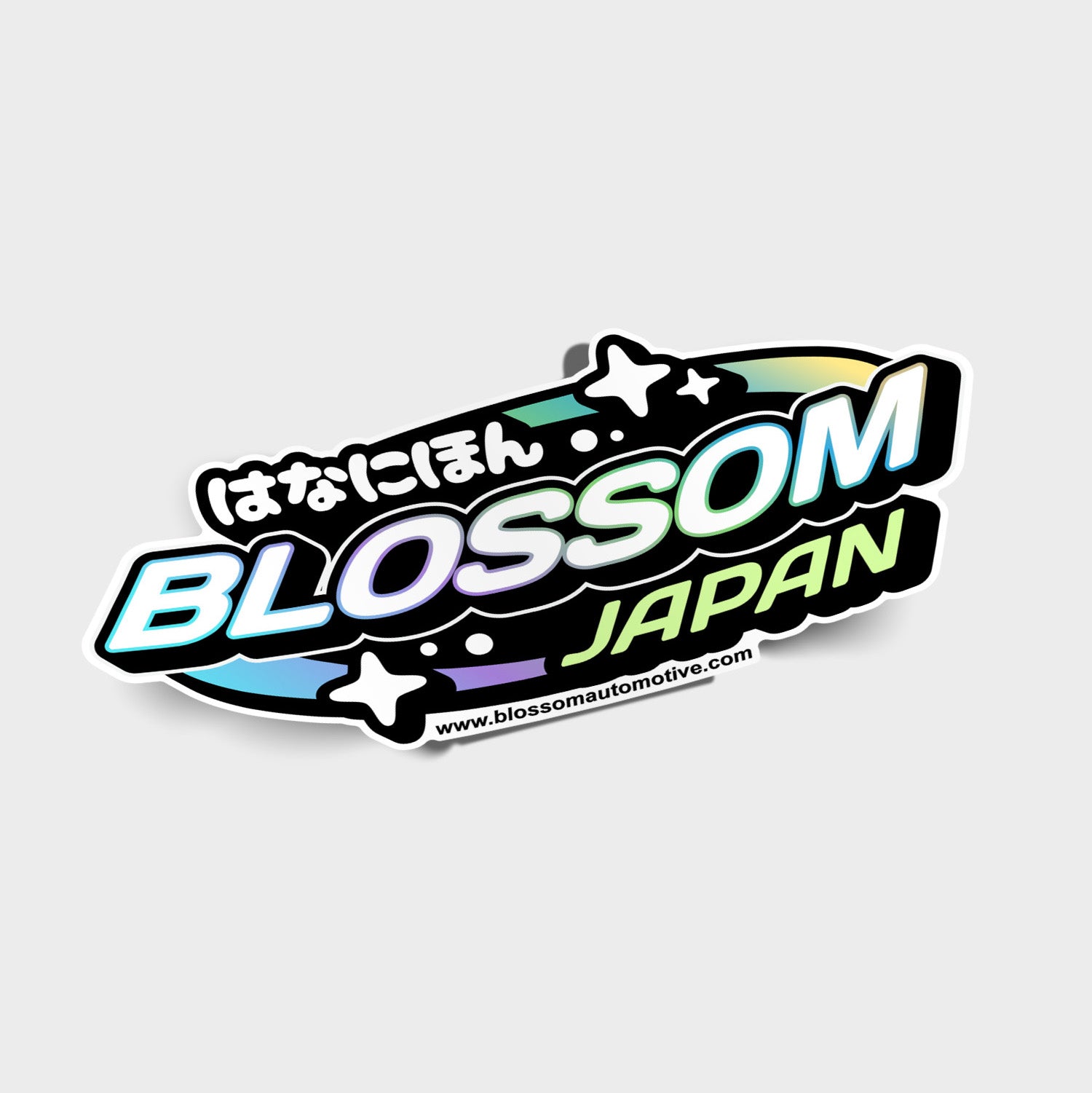 The Blossom Japan - Slap Sticker by Blossom Automotive features “Blossom Japan” text with Japanese characters, sparkles, and a rainbow gradient. The website www.blossomautomotive.com is printed at the bottom.