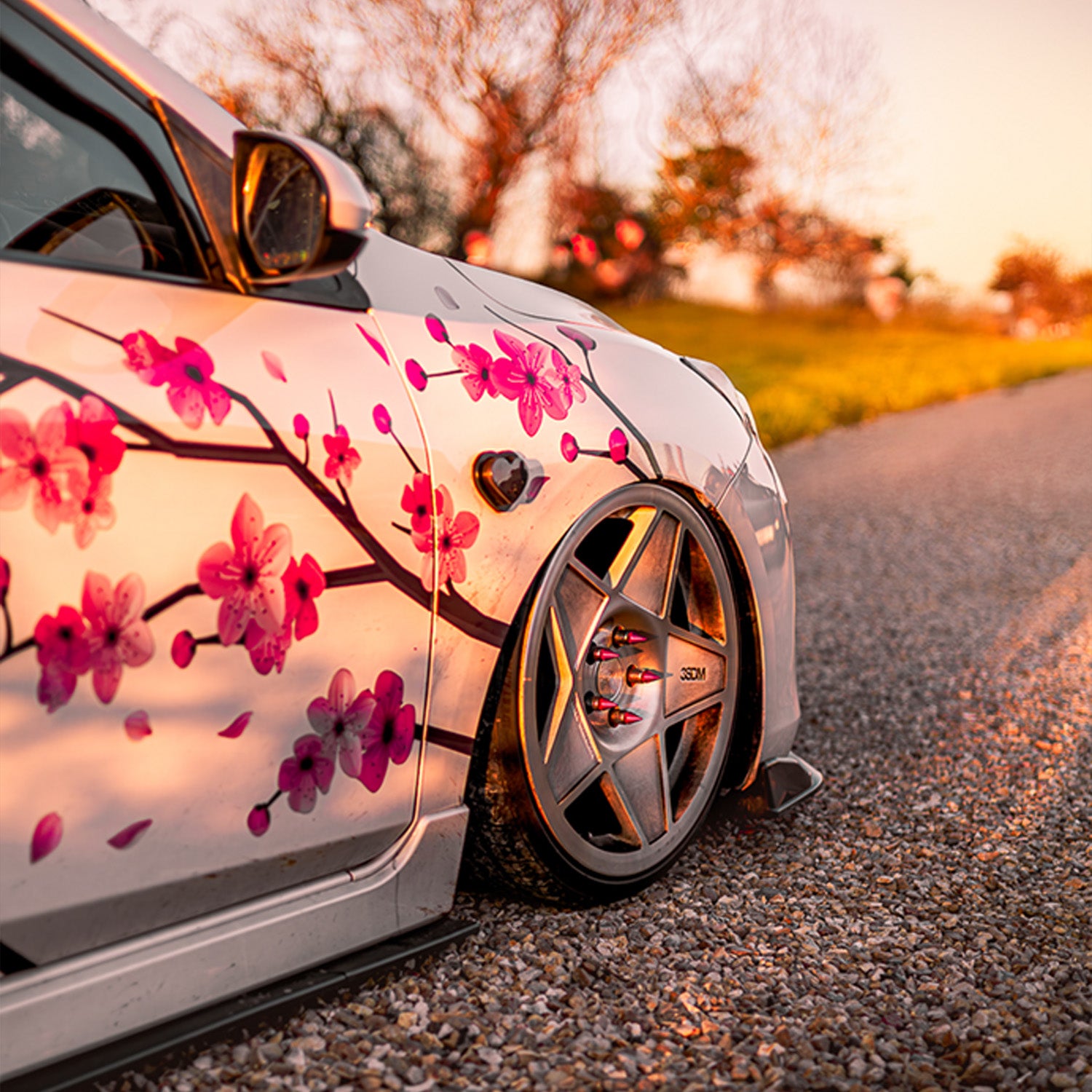 Car with cherry blossom design on a road during sunset