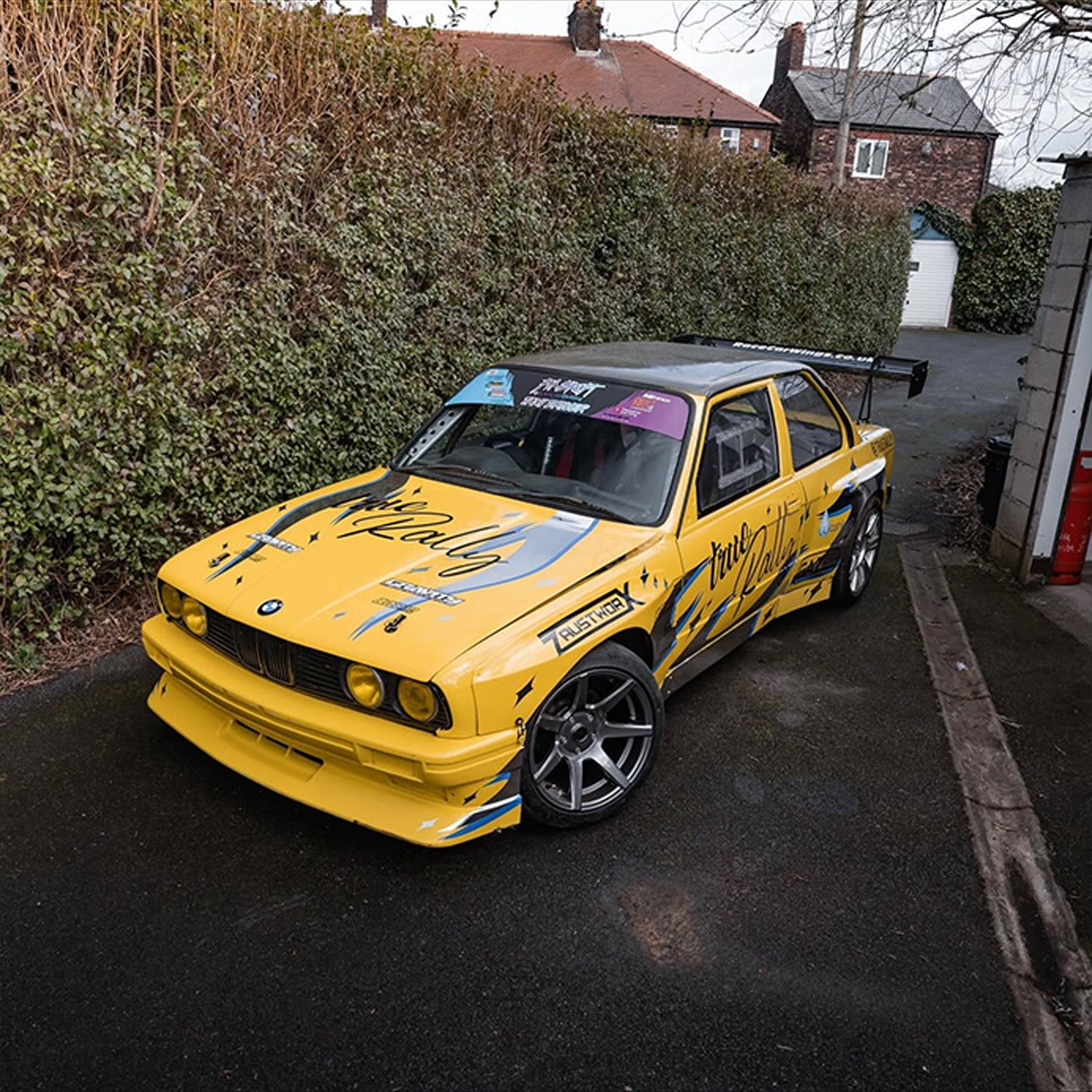 Yellow race car parked with Blossom Automotive Zoku tribal livery on it