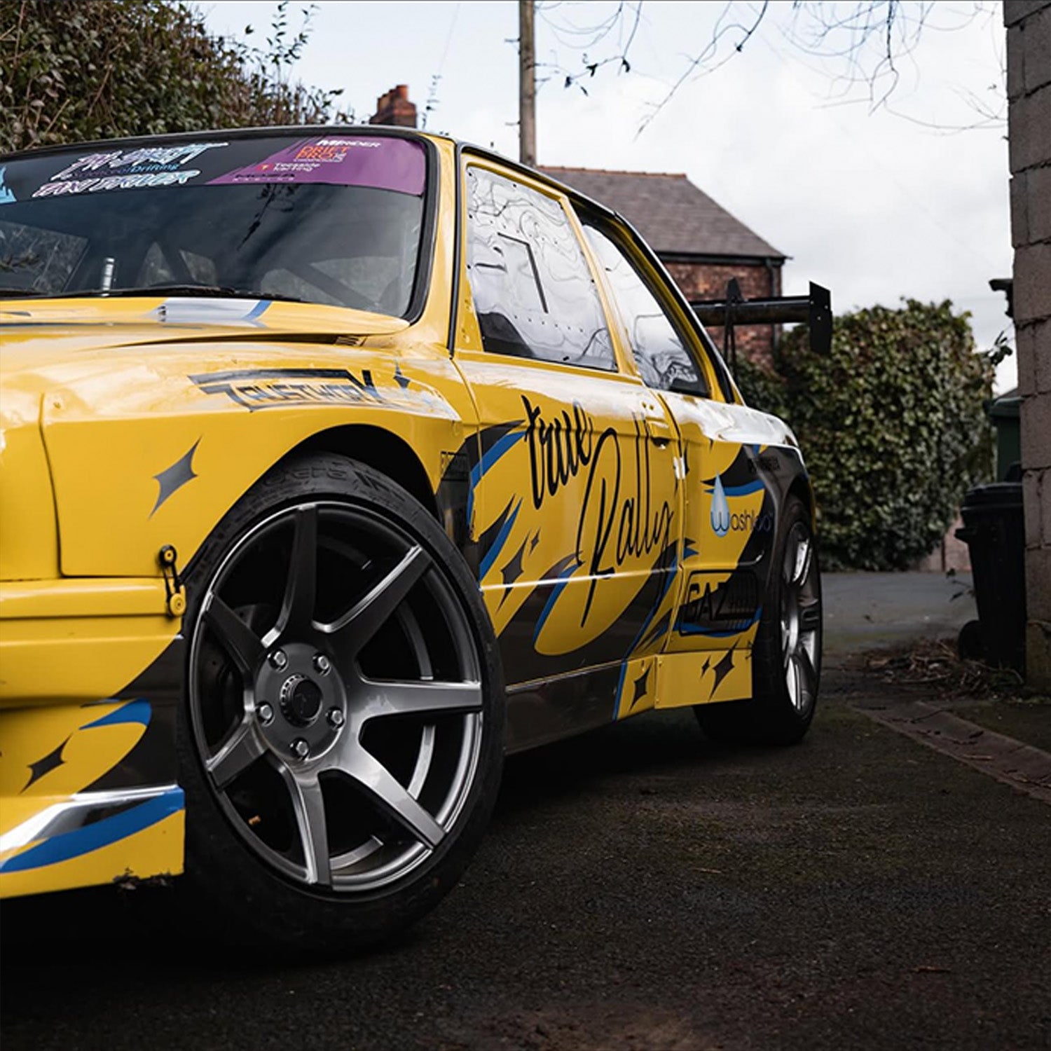 Yellow race car parked with Blossom Automotive Zoku tribal livery on it
