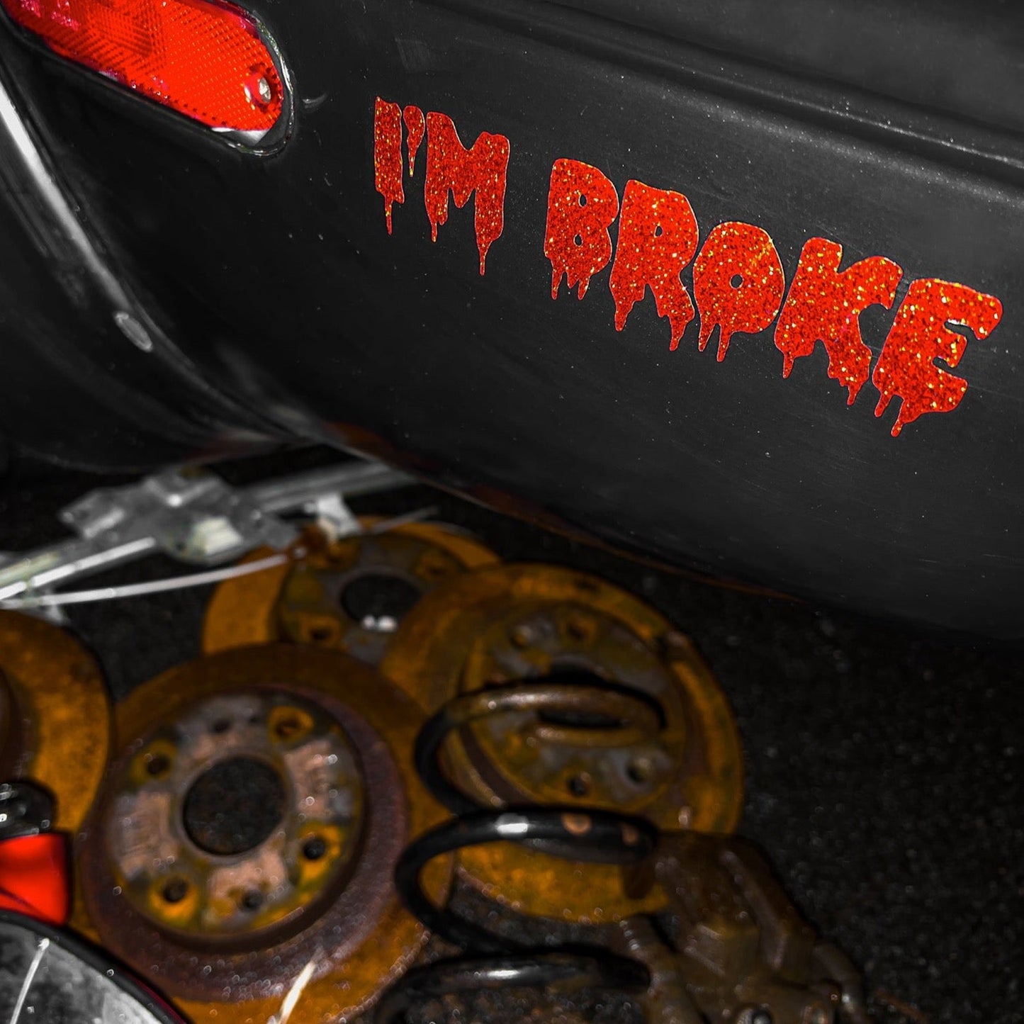 I'm broke die cut sticker in sparkles red on a Miata