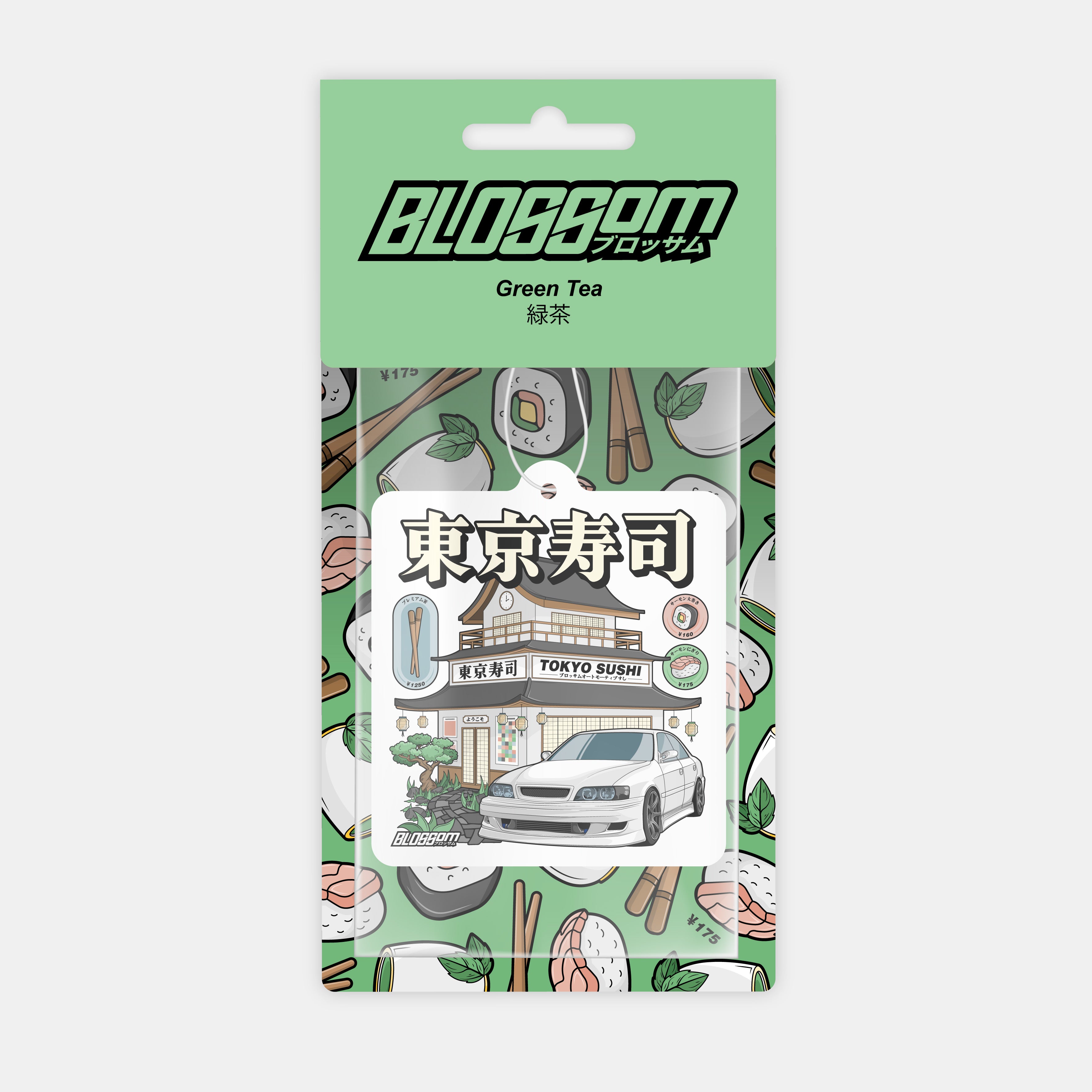 The Blossom Automotive 'Tokyo Sushi' Air Freshener - Green Tea features Tokyo sushi restaurant and sushi graphics, a white car, Japanese text, and vibrant sushi illustrations on its packaging.