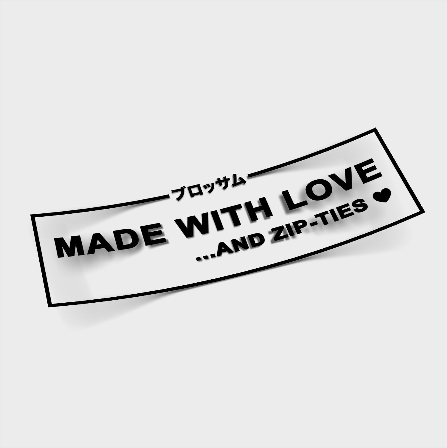 A white die cut sticker from Blossom Automotive features "ブロッサム" at the top and "MADE WITH LOVE ...AND ZIP-TIES ♥" in bold black text on a plain light background. Product name: Made With Love... And Zip-Ties - Die Cut Sticker.