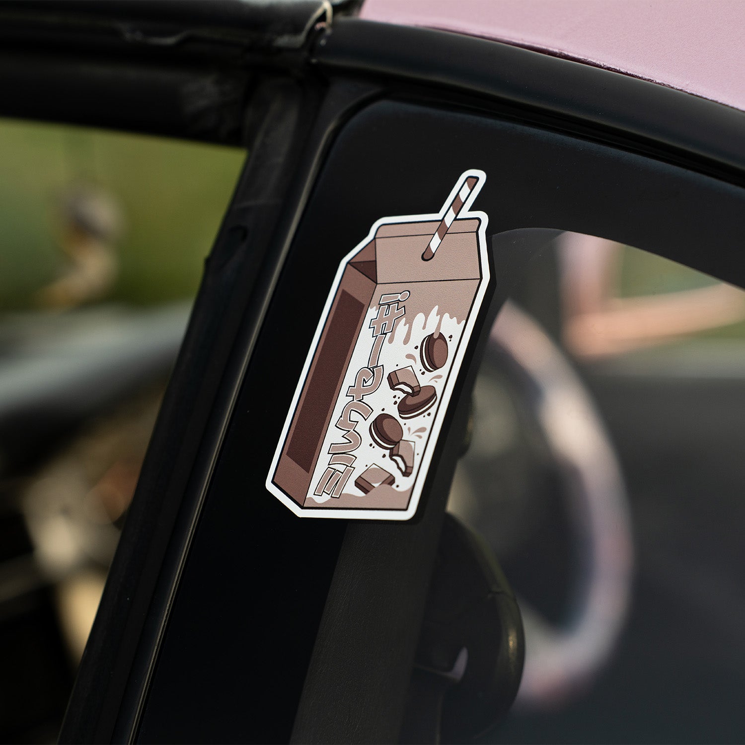 A large Blossom Automotive "Cookies and Cream Milkshake - Slap Sticker" with spilled milk, cookies, a striped straw, and stylized text decorates the car’s black window pillar.