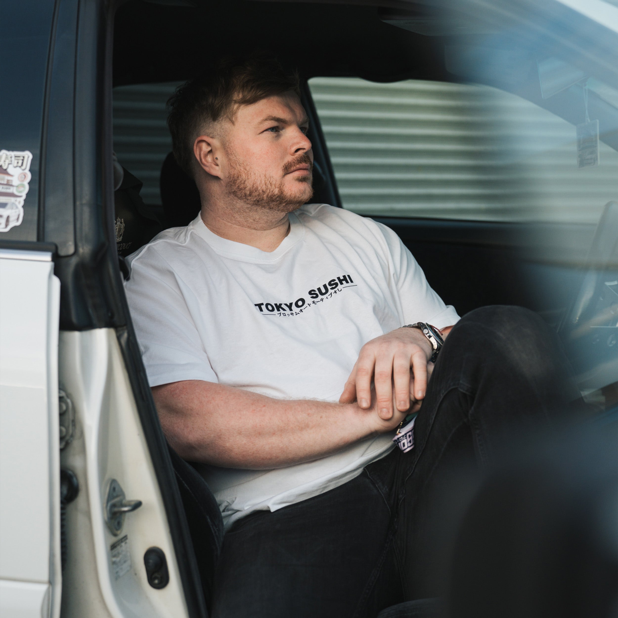 person wearing white Tokyo sushi collection t-shirt sat in white Toyota chaser