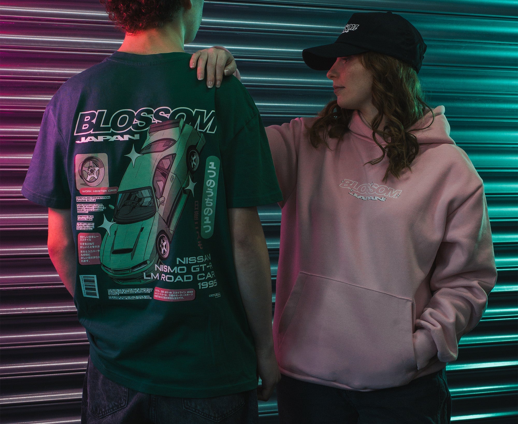 person wearing the skate collection hoodie while looking under bonnet of green is200 car