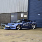 Blue sports car with white floral design parked in front of a building