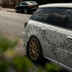 White car with black floral decals parked on a street