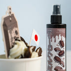 A close-up of a paper cup with whipped cream and Oreos, adorned with a small Japanese flag. Next to it is Blossom Automotive’s 'The Milkshake Collection' Car Spray Air Freshener - Cookies & Cream 200ml, featuring cookie graphics on the label.