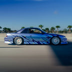 Blue car with flame design on a road with palm trees in the background