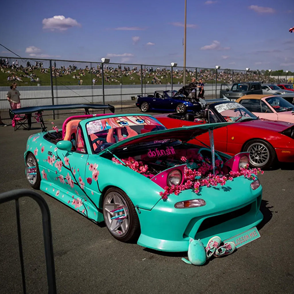 Turquoise car with floral Blossom Automotive decorations at a car show