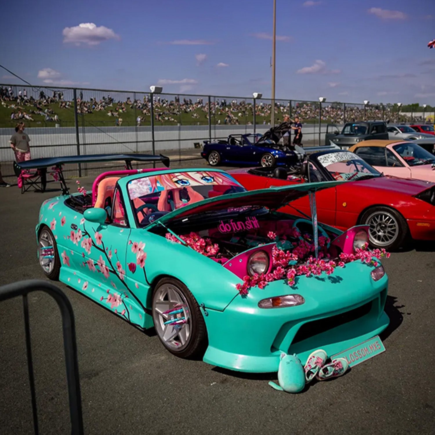 Turquoise car with floral Blossom Automotive decorations at a car show