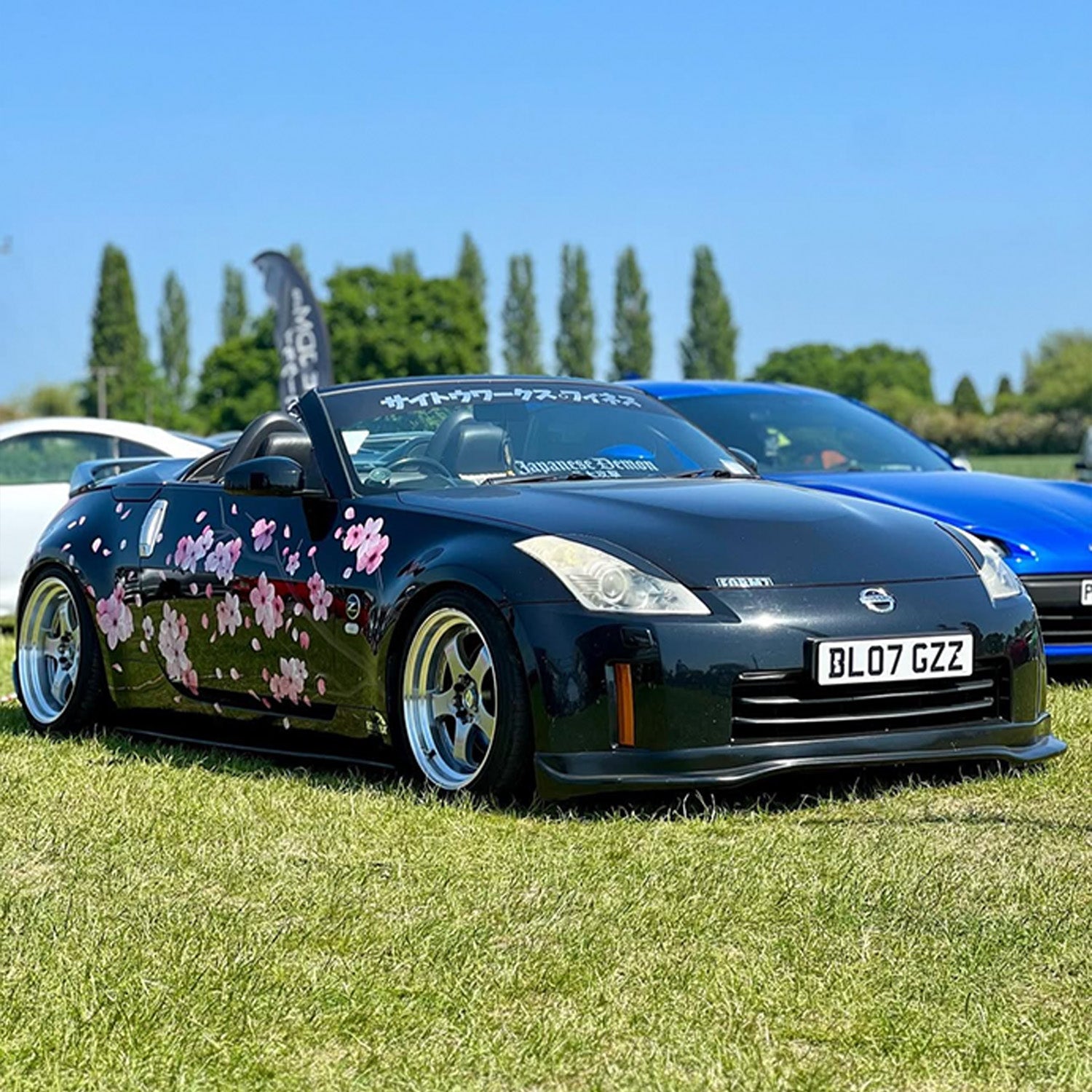 Black Nissan car with floral Blossom design on grass