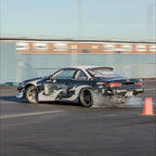 Black and white drift car on a track with blurred background and Blossom Automotive Zoku livery on it
