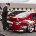 Person cleaning a red car with Blossom Zoku livery branding in an outdoor setting