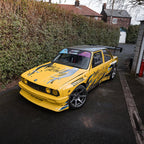 Yellow race car parked with Blossom Automotive Zoku tribal livery on it