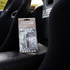 A Blossom Automotive 'The Milkshake Collection' Air Freshener in Cookies & Cream scent sits packaged on the black leather seat of a car with Blossom Automotive-branded bucket seats.
