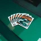 The Skate Collection - Slap Sticker by Blossom Automotive features a green car, flames, and stylized orange Blossom text, displayed on a glossy green surface.