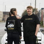 Two individuals standing next to a white mx5, wearing black crewneck t-shirts with a yellow graphic design on the back, featuring a white mx5.