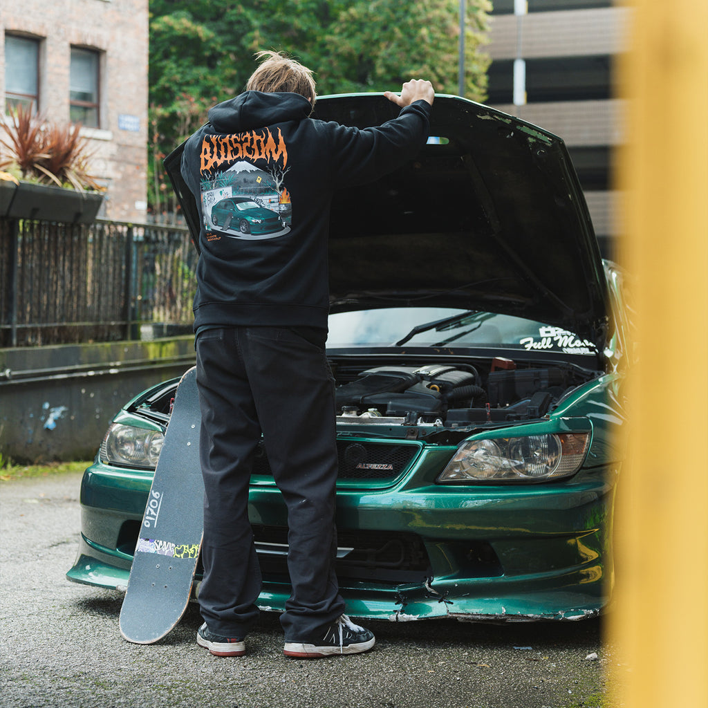 a person looking under the hood of a green is200 wearing the black skate collection hoodie