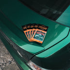 Five 'The Skate Collection' Air Fresheners in Blood Orange by Blossom Automotive, each featuring a car graphic, are displayed on the trunk of a shiny green car outdoors in daylight.