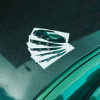 Five Blossom Automotive IS200 - Slap Stickers with green sports car art are fanned out on a shiny, dark car hood, reflecting their vivid green color and light specks from the paint.