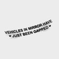 The Blossom Automotive Vehicles in Mirror Have Just Been Gapped Die Cut Sticker features black, bold curved text with small black hearts on each side, set against a plain white background.