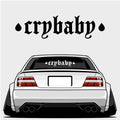 Illustration of a white modified car viewed from the rear, featuring Blossom Automotive’s Crybaby - XL Rear Window Die-Cut Sticker in gothic font on the windshield and two black teardrop shapes above the car.