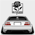 A white car with wide cambered tires is viewed from the rear, featuring Blossom Automotive’s No F*cks Given - XL Rear Window Die-Cut Sticker with a rose decal displayed above and on the rear window.